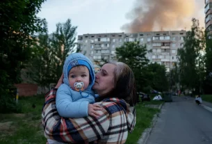 Мати тримає дитину біля ураженого обстрілом Росії житлового будинку