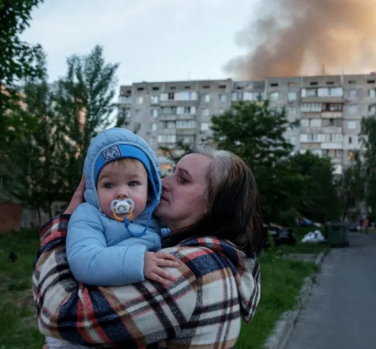 Мати тримає дитину біля ураженого обстрілом Росії житлового будинку