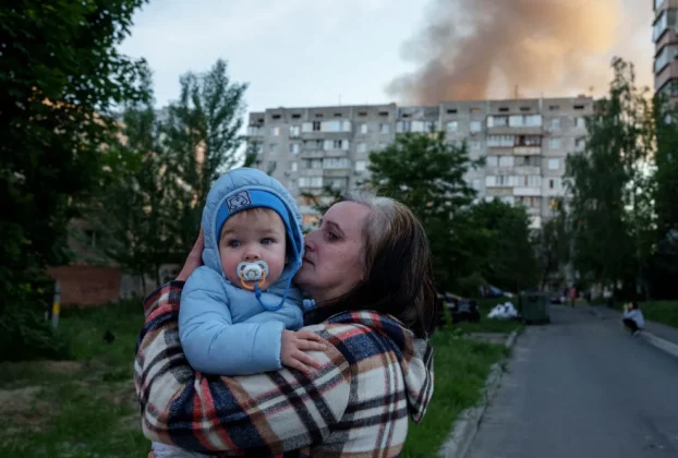 Мати тримає дитину біля ураженого обстрілом Росії житлового будинку