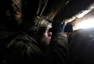 солдат у бліндажі дивиться у бінокль