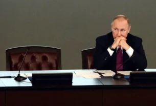 Володимир Путін сидить за столом з порожнім поруч місцем