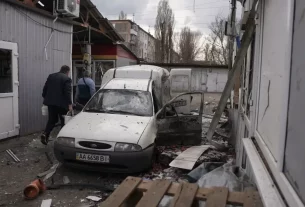 Люди розчищають уламки на ринку, який 4 квітня 2026 року зазнав удару російського безпілотника, у Нікополі, Україна