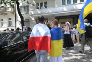 люди обгорнуті у прапори Польщі та України стоять поручь