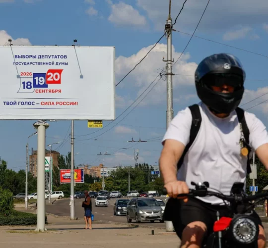 Велосипедист проїжджає повз рекламний щит, на якому анонсуються парламентські вибори в Росії, заплановані на вересень, під час російсько-українського конфлікту в Донецьку — місті України, що перебуває під контролем Росії, 7 серпня 2026 року