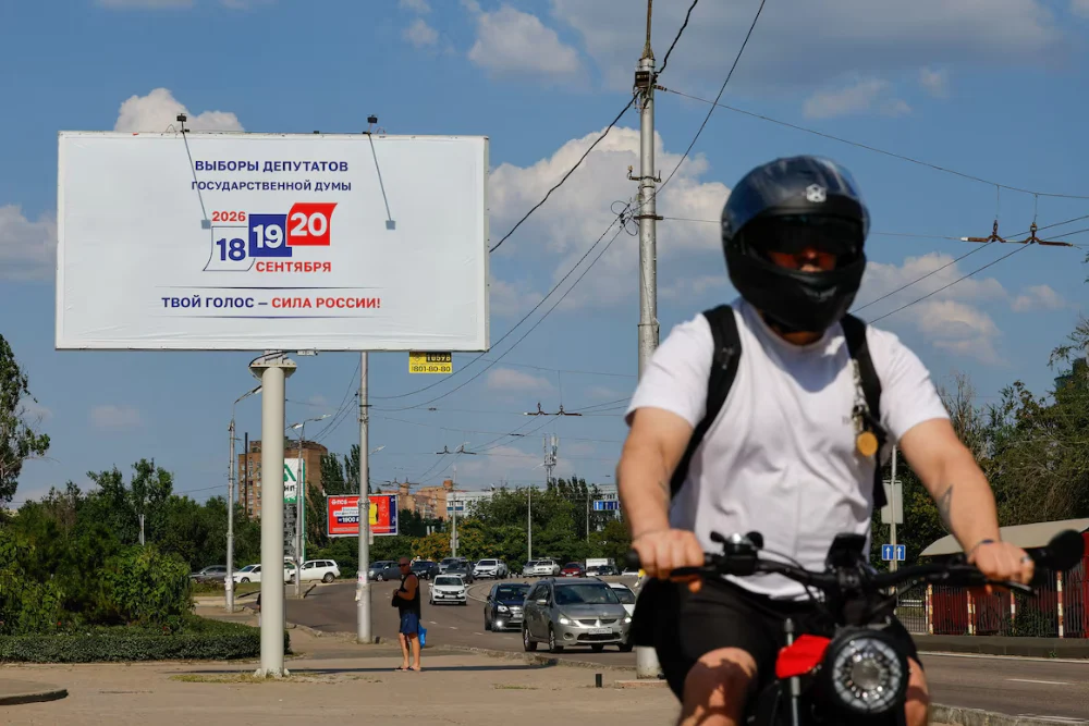 Велосипедист проїжджає повз рекламний щит, на якому анонсуються парламентські вибори в Росії, заплановані на вересень, під час російсько-українського конфлікту в Донецьку — місті України, що перебуває під контролем Росії, 7 серпня 2026 року