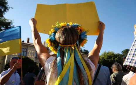 українка з вінком на голові та плакатом у руках