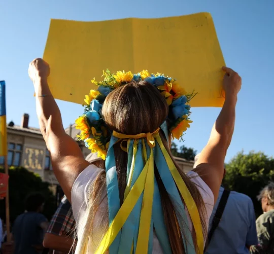 українка з вінком на голові та плакатом у руках