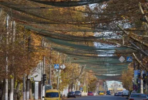 Місцеві жителі йдуть вулицею, вкритою сіткою проти дронів FPV, у прифронтовому місті Херсон на півдні України, 3 листопада 2025 року