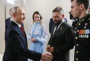 Президент Росії Володимир Путін (ліворуч) вітає Владислава Головіна (праворуч) під час зустрічі з керівниками політичної партії «Єдина Росія» у присутності уповноваженої президента з прав дітей Марії Львової-Белової (у центрі) та військового кореспондента Євгена Поддубного (другий праворуч) у Москві в суботу, 5 вересня 2026 року