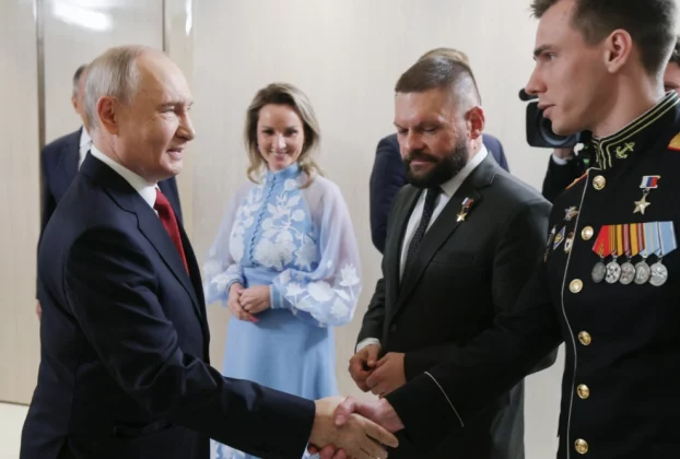 Президент Росії Володимир Путін (ліворуч) вітає Владислава Головіна (праворуч) під час зустрічі з керівниками політичної партії «Єдина Росія» у присутності уповноваженої президента з прав дітей Марії Львової-Белової (у центрі) та військового кореспондента Євгена Поддубного (другий праворуч) у Москві в суботу, 5 вересня 2026 року