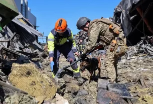 Рятувальники з собакою працюють на місці торгового центру, зруйнованого вчорашнім ударом російського безпілотника в рамках російського вторгнення в Україну, у місті Кривий Ріг, Дніпропетровська область, Україна, 22 серпня 2026 року