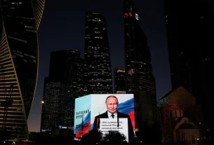 Володимир Путін транслюється на великому екрані під час святкування його дня народження в Москві