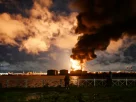 Люди спостерігають за палаючим нафтовим терміналом після авіаудару в Санкт-Петербурзі, Росія, 18 жовтня 2026 року